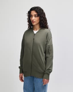 A model wearing an olive green unisex bomber jacket with a zip and side pocket.