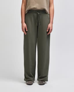 Wide leg pants in olive green with a drawstring waistband, featuring a relaxed fit and a logo on the waistband.