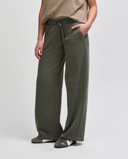 Wide leg pants in olive green with a drawstring waist and side pockets, styled with a casual top.