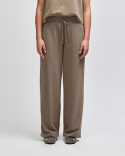 Wide leg women's pants in a light brown colour with an elastic waistband and drawstring. Features branding on the garment.