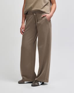 Wide leg pants in brown French terry fabric. Features a drawstring waist and side pockets. Appears on a mannequin.