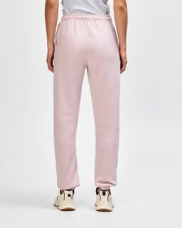 Unisex sweatpants in a soft pink hue, featuring elastic cuffs and a neat fit at the back. Brand logo present.