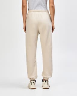 Unisex sweatpants in a beige colour with an elasticised waistband and cuffs, featuring a visible logo.