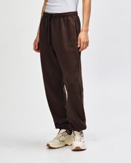 Brown unisex sweatpants with a drawstring waist, featured alongside black sneakers. The pants have a logo.