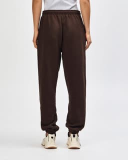 Brown unisex sweatpants with an elastic waistband, featuring a logo on the back. Casual style and relaxed fit.