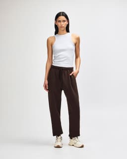 Unisex sweatpants in brown with an elastic waistband; styled with a matching brown hoodie. Features a branding logo.