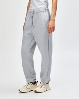 Grey unisex sweatpants made of fleece, featuring a drawstring waist and side pockets. Styled with sneakers.