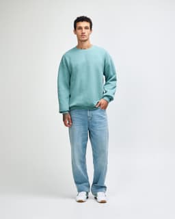 A unisex crewneck sweatshirt in green, paired with black cargo pants, featuring a logo on the front.