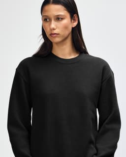 A black unisex crewneck sweatshirt with long sleeves, featuring a logo on the front.