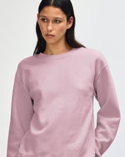 A unisex crewneck sweatshirt in a soft pink hue, featuring a casual design and a logo on the sleeve.