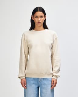 A unisex cream sweatshirt made from fleece with a crewneck design and ribbed cuffs. It has a branding logo.