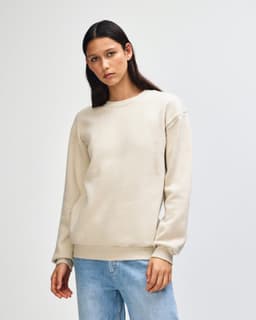 A unisex crewneck sweatshirt in a light beige colour, featuring a simple design and a logo on the chest.