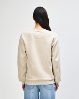 A unisex crewneck sweatshirt in a light beige colour, featuring a logo on the back and ribbed cuffs.