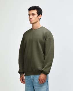 A unisex crewneck sweatshirt in green, featuring long sleeves and a relaxed fit, with a logo at the hem.