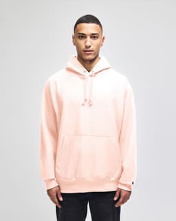 A light pink pullover hooded sweatshirt with a front pocket and a logo on the sleeve.