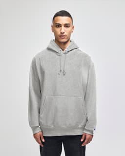 A grey hooded sweatshirt with a front pocket and a logo. Styled with a relaxed fit and drawstrings at the hood.
