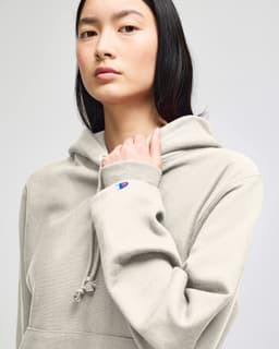 A light grey hooded sweatshirt featuring a kangaroo pocket and a logo on the sleeve.