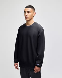 A black Champion Reverse Weave® adult crew sweatshirt displayed on a model, featuring a logo on the sleeve.