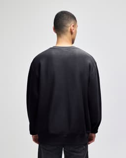 A black crew sweatshirt with a relaxed fit, featuring long sleeves and a back view. It has a logo.