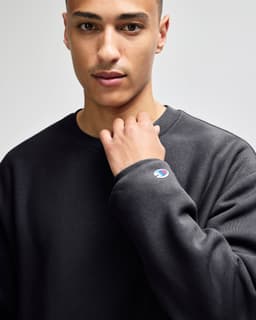 A dark grey sweatshirt with a crew neckline and a small logo on the sleeve.