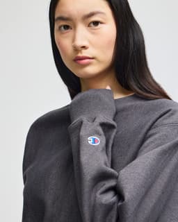 A grey Champion Reverse Weave® adult crew sweatshirt with a logo on the sleeve.
