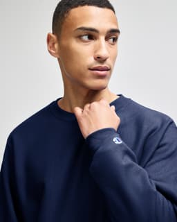 A navy blue Champion Reverse Weave® adult crew sweatshirt with a logo on the sleeve.