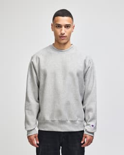 A grey Champion Reverse Weave® adult crew sweatshirt with long sleeves and a logo on the sleeve.