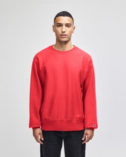 A red Champion Reverse Weave® adult crew sweatshirt displayed on a model. The sweatshirt features a logo tag.