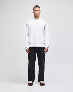 A grey Champion Reverse Weave® adult crew sweatshirt worn by a model with dark trousers and shoes.