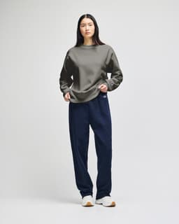 A grey Champion Reverse Weave® adult crew sweatshirt worn by a model, paired with dark trousers and shoes.