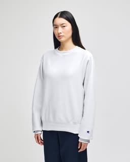 A light grey adult crew sweatshirt with a relaxed fit, featuring a logo on the sleeve.