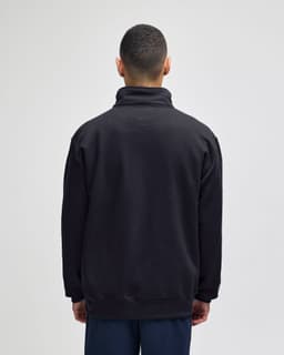 A black quarter-zip pullover with a high collar and a relaxed fit, featuring a logo on the back.