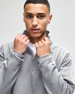 A grey quarter-zip pullover with a collar, featuring a branding logo on the sleeve.