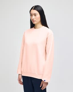 A beige crewneck sweatshirt with long sleeves, featuring a small logo on the sleeve.