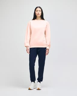 A model wears a beige Champion Powerblend® adult crewneck sweatshirt paired with navy trousers and white sneakers.