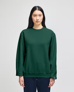 A green Champion Powerblend® adult crewneck sweatshirt displayed on a model, featuring a logo on the sleeve.