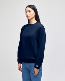 A navy blue crewneck sweatshirt with long sleeves, featuring a logo on one sleeve.