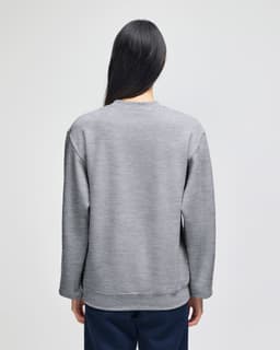 A grey adult crewneck sweatshirt featuring a logo on the back, displayed on a model from the rear.