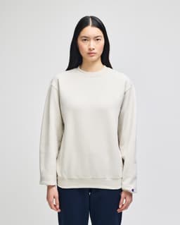 A cream-coloured adult crewneck sweatshirt with long sleeves and a logo on the sleeve.