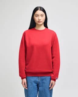 A red crewneck sweatshirt displayed on a model, featuring long sleeves and a logo.