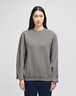 A grey crewneck sweatshirt with a logo, featuring long sleeves and a relaxed fit.