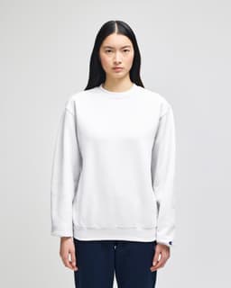 A white crewneck sweatshirt made from Champion Powerblend® fabric, featuring a logo on the sleeve.