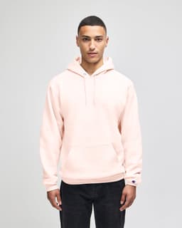 A pullover hooded sweatshirt in a taupe colour, featuring a logo on the sleeve, worn by a model.