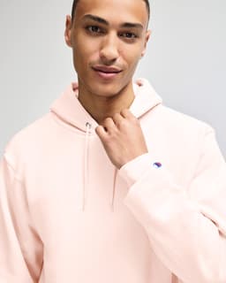 A man models a taupe Champion Powerblend® adult pullover hooded sweatshirt with a logo on the sleeve.