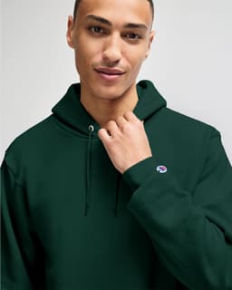 A green hooded sweatshirt with a fitted design and a small logo on the sleeve, worn by a model.