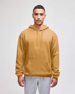 A plain mustard-coloured pullover hooded sweatshirt with a front pocket and a logo. The model is wearing grey pants.
