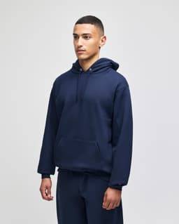 A navy hooded sweatshirt featuring a front pocket and a casual fit, modelled by a young man.
