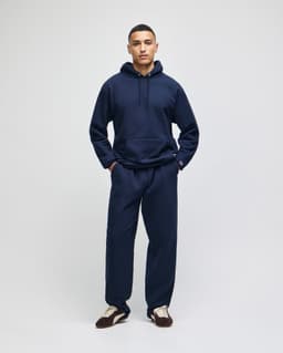 A navy pullover hooded sweatshirt paired with matching pants, featuring a logo on the sweatshirt.