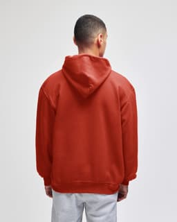 A red pullover hooded sweatshirt with a large hood, seen from the back. Features a logo on the garment.