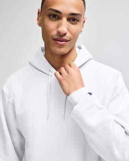 A white pullover hooded sweatshirt with a logo, worn by a person with short hair.